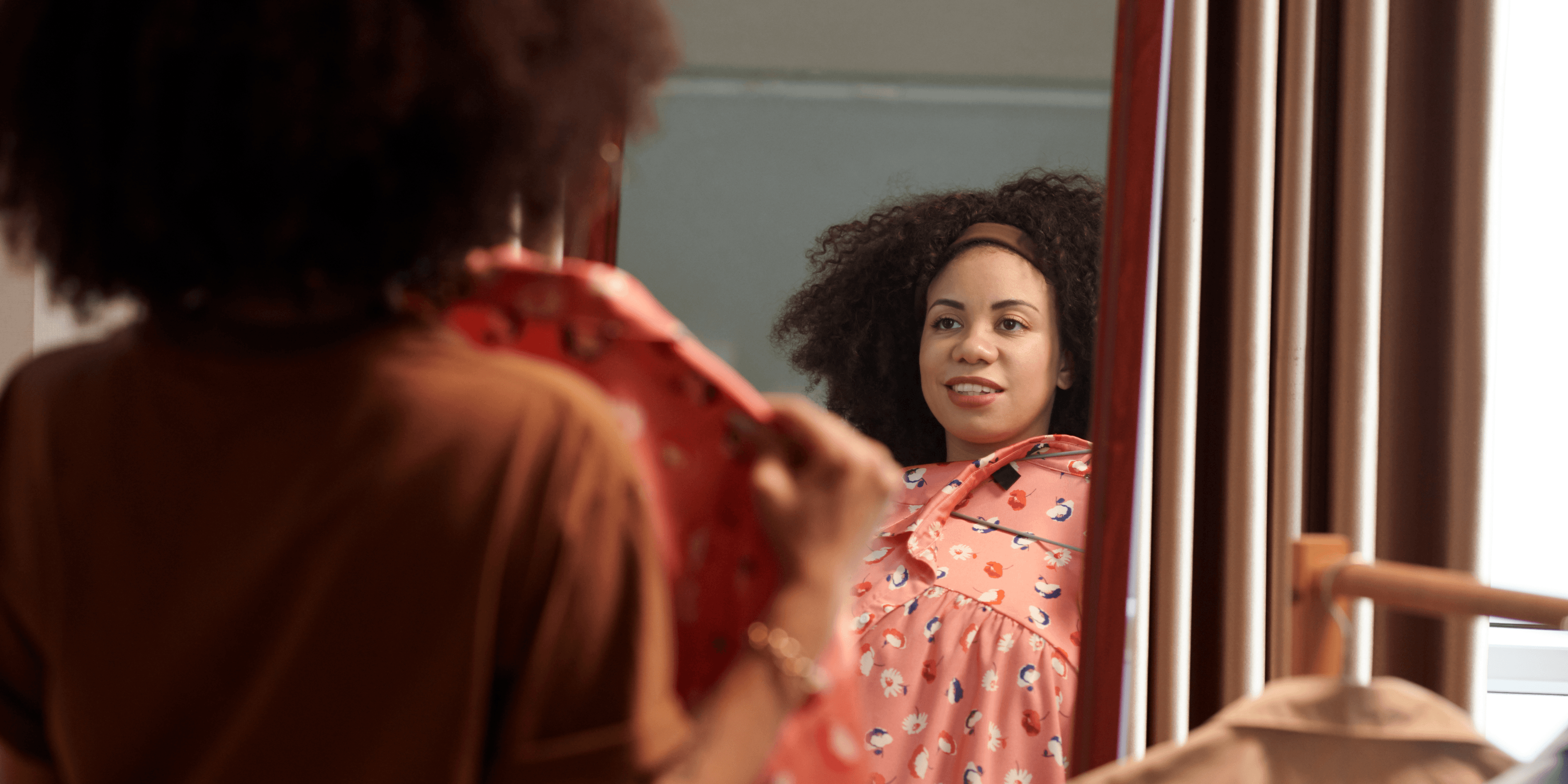 Woman trying a floral outfit in front of a mirror